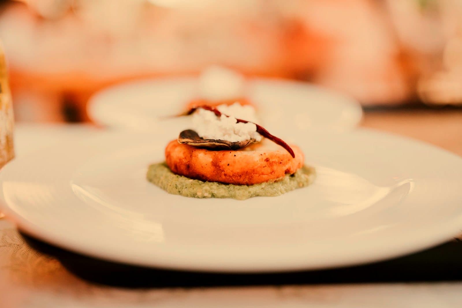 A gourmet dish elegantly plated with an appetizer served on a white plate in a restaurant setting.
